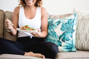 Beautiful woman in workout clothing eating a salad